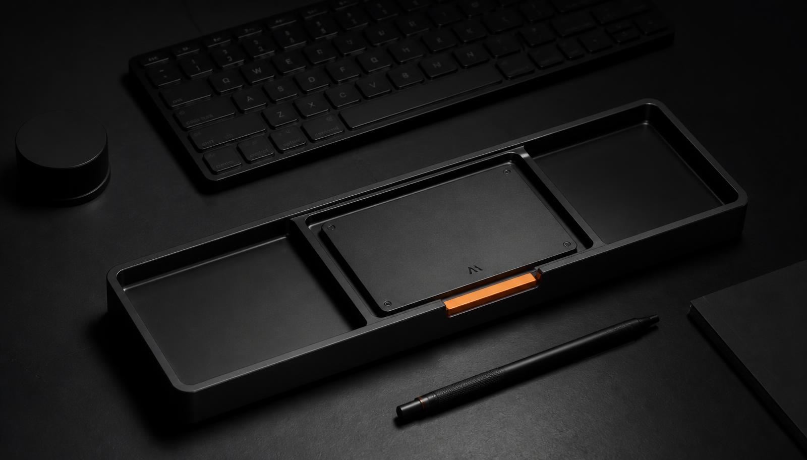 AM‑01 keyboard and machined desk tray on a matte black surface